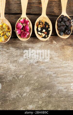 Collection of tea and natural additives in wooden spoons, on old wooden table Stock Photo