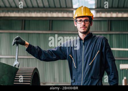 Happy worker nerdy glasses working in industry factory hand with wrench wear safety suit and helmet. Stock Photo