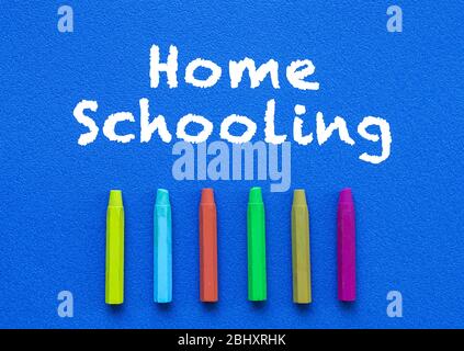 Homeschooling. Words or typed text on blue board. Colorful crayons. Top view. Education concept. Stock Photo