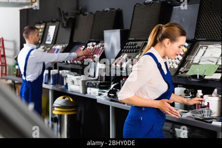 Smiling cheerful  female car painter preparing paints for paintwork in modern auto repair shop Stock Photo
