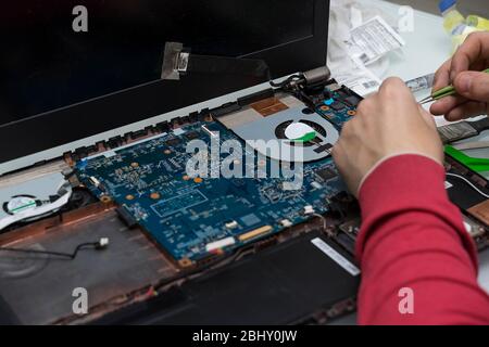 hands of the master are repairing a laptop. laptop disassembled. computer repair Stock Photo