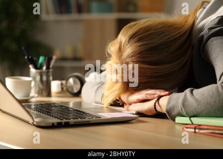 Close up of tired student girl sleeping over desk at home in the night Stock Photo
