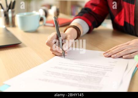 Close up of student girl hands signing contract sitting on a desk at home Stock Photo