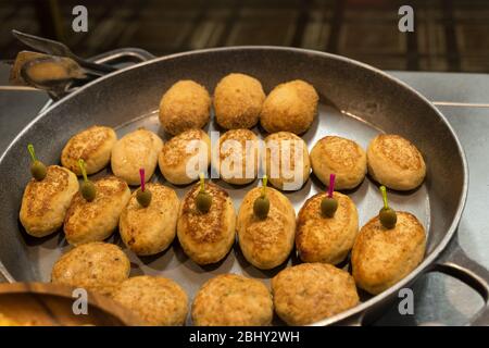 ready-made potato pancakes of different types lie in a large frying pan in the open kitchen of the restaurant Stock Photo
