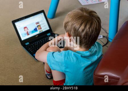 Caucasian boy studying using a laptop in his bedroom for home schooling, UK Stock Photo