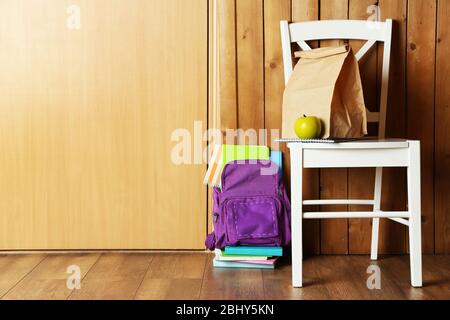 Backpack with school supplies on chair on wooden background Stock Photo
