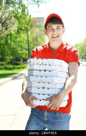 Young man delivering pizza box outdoors Stock Photo