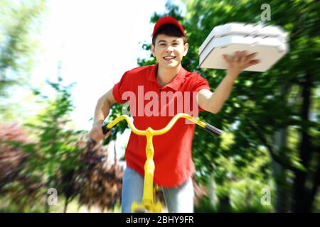 Young man delivering pizza box on bike outdoors Stock Photo