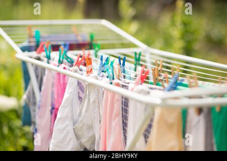 A kind of different clothes hanging on a dryer fixing by colorful pins Stock Photo