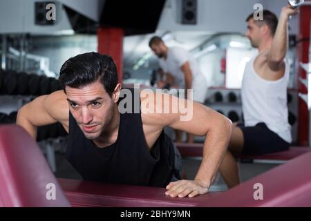 Strong sporty man doing push-ups on bench during workout in gym Stock Photo
