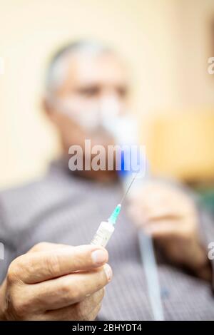 Senior man using medical equipment for inhalation with respiratory mask, nebulizer in the room Stock Photo