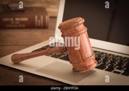 wooden judges gavel on keyboard laptop computer at law fiam. Stock Photo