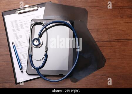 Stethoscope, clipboard, x-ray and tablet on wooden background Stock Photo