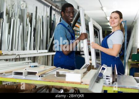 Two masters are working with window frame in the window workshop. Stock Photo