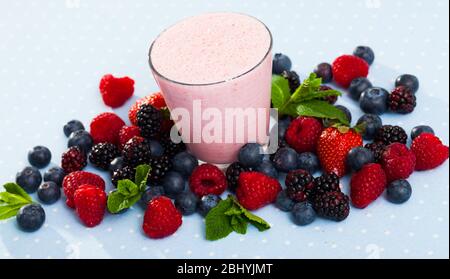 Healthy vitamin milkshake with mix of ripe berries and mint leaves served in glass Stock Photo