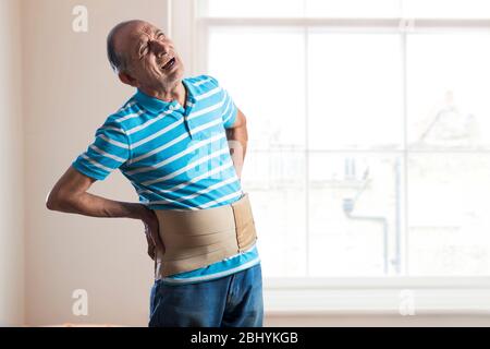 Old Man with Back Pain Wearing Back Support Belt or Medical Belt