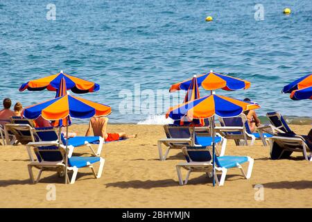 Beach scene of beach loungers and parasols on the Spanish Canarian Isla de Lanzarote and view of the Atlantic ocean. Stock Photo