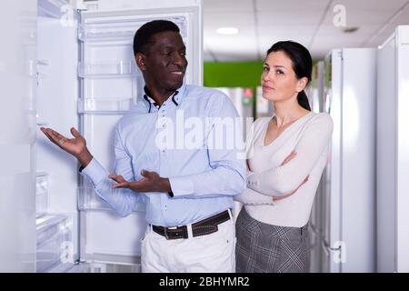 Spouses are discussing the purchase of a refrigerator in a home appliance store Stock Photo
