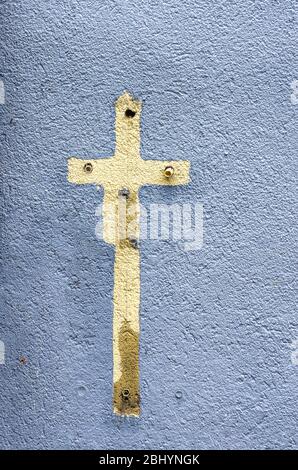 Imprint of a cross sign surrounded with colour on a house wall full of old expansion dowels. Stock Photo