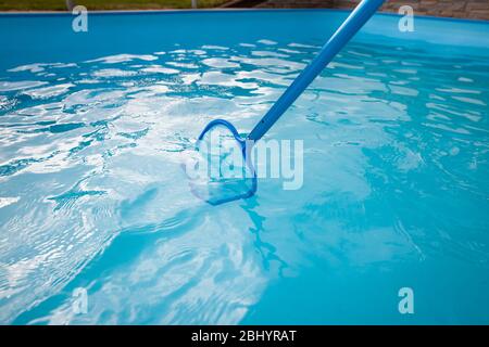 Young man hands cleaning pool by net of the dust, maintenance, clearing swimming pool Stock Photo