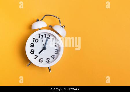 White vintage alarm clock on yellow color background Stock Photo