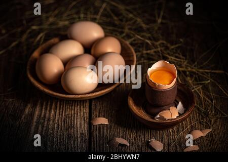 Whole and broken raw brown eggs on wooden table Stock Photo