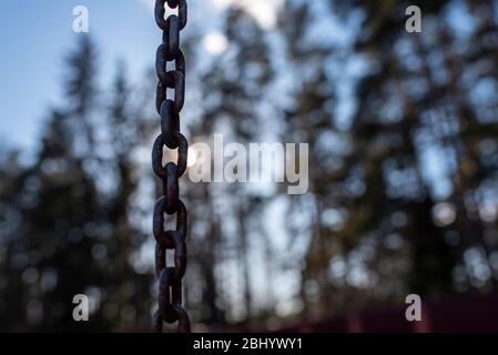 A rusty chain amid the sun and sky. Stock Photo
