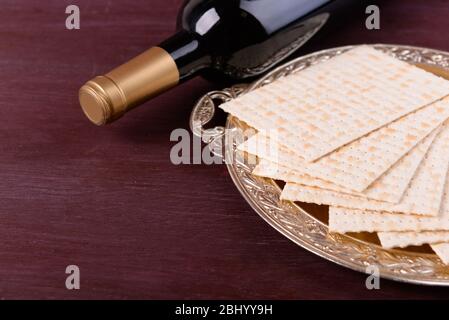 Matzo for Passover on metal tray with bottle of wine on table close up Stock Photo