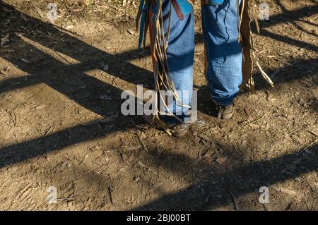 Cowboy legs with jeans, chaps, boots and spurs in the raking afternoon sun with his legs and rodeo rail shadows at Mareeba in Australia. Stock Photo