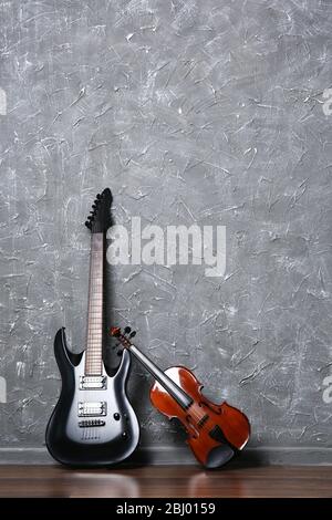 Electric guitar and violin on gray wall background Stock Photo