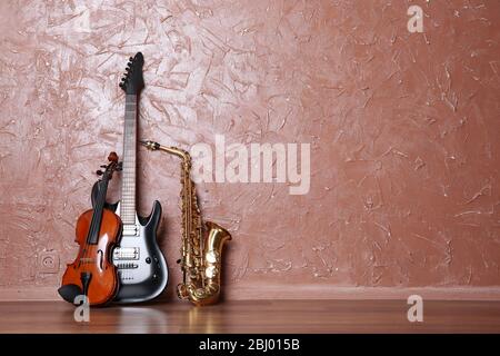 Electric guitar, saxophone and violin on brown wall background Stock Photo