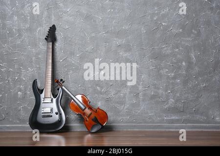 Electric guitar and violin on gray wall background Stock Photo