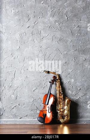 Violin and saxophone on gray wall background Stock Photo