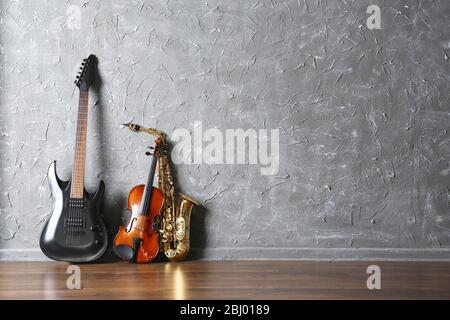 Electric guitar, saxophone and violin on gray wall background Stock Photo