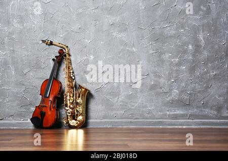 Violin and saxophone on gray wall background Stock Photo