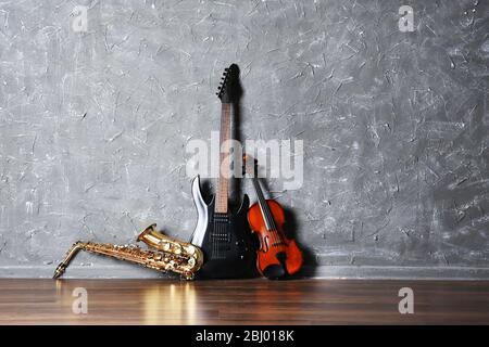 Electric guitar, saxophone and violin on gray wall background Stock Photo