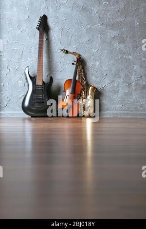 Electric guitar, saxophone and violin on gray wall background Stock Photo