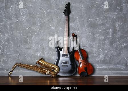 Electric guitar, saxophone and violin on gray wall background Stock Photo