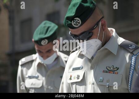 Jerusalem, Israel 28th April 2020, An Israeli border policemen wearing protective mask due to the COVID-19 coronavirus pandemic stand still in downtown Jerusalem as a siren sounds for two minutes in memory of Fallen Soldiers and Victims of Terrorism on Israel's official remembrance day. Stock Photo