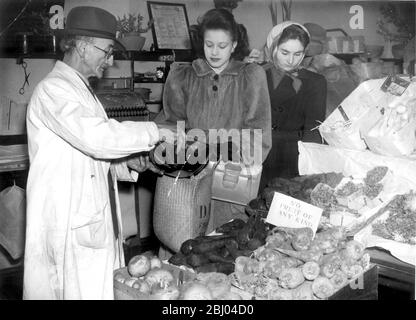 Potatoes are usually plentiful - just along the road from her grocer's Mrs Gill gets 7lb of potatoes from her greengrocer Mr Ferraro - No fruit of any kind says the card ( all cards say NO ) which is what Mrs Gill expected - Oranges now come in every few months - Babies can get a pound on their green ration books and what's left over goes to the grown ups - Bananas are now very occasionally seen in London ( half a pound for under eighteens ) - 1946 Stock Photo