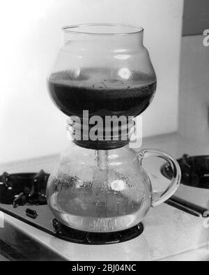1950's coffee maker - As the water heats, it forces its way up into the top bowl. Water below the end of the glass stays in the jug and so prevents the jug boiling dry and causing any damage to the glass. Stock Photo