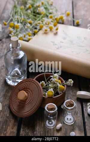 Old book with dry flowers in mortar on table close up