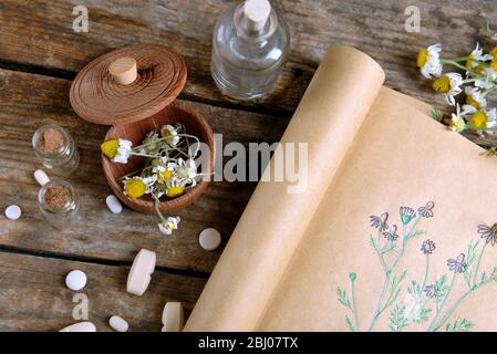 Old book with dry flowers in mortar on table close up
