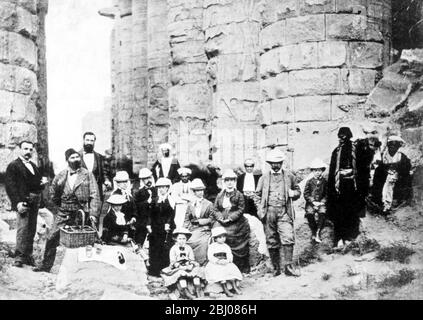 A family picnic at Karnak. Pierpont is standing with the stick, with Mrs Morgan on his right, Jack on his left, and his daughters, Annie (by the basket), Juliet and Louisa, sitting in front. The native standing on the right is the Consular Agent at Luxor; beside him is Jack, then Pierpont, his wife, and Mary Huntington, Abbie, the nurse, Caesar, Mrs Gibbons the maid, the dragoman, and Clemmy the waiter. Behind the dragoman is the doctor. The little girls (right to left) are Annie, Juliet, and Louisa. Stock Photo