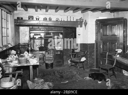 The kitchen of Old Hall Farm , with its raftered ceiling , black leaded range and accumulation of ornaments and old time equipment , including an oil lamp . Stock Photo
