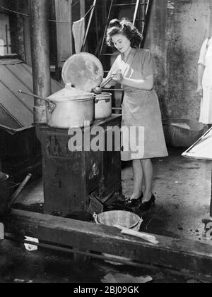 Beating the gas strike. - J Lyons and Company's London engineers have been working through the night on emergency cooking arrangements to combat the gas shortage caused by the unofficial strike of 2000 maintenance engineers of the Gas Light and Coke Company. Every available method of heating is being used, including oil stoves, field kitchens and open fires. The normal amount of bread, cakes and food was cooked today (Monday) but in some cases Lyons may be obliged to serve meals of the wartime 'blitz' variety. - Photo shows, cooking on an open fire in a Lyons Cafe in the City of London, today, Stock Photo