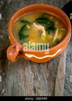 Complete meal soup of chicken, chorizo sausage and vegetables with brown rice, lentils and spinach, served in pale blue bowl Stock Photo