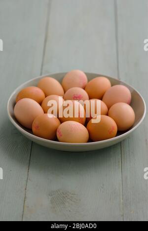 Dish of brown eggs on painted surface - Stock Photo