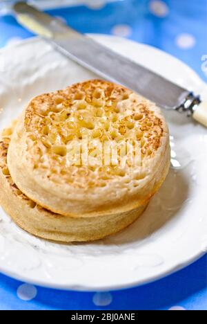 Hot buttered crumpets on white plate - Stock Photo
