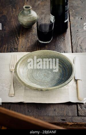 Rustic table setting with tumbler of red wine before food arrives - Stock Photo